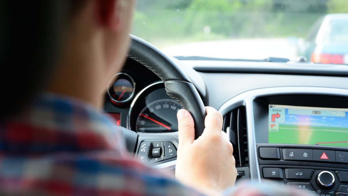 Nouvelles règles du code de la route 2025 - Conducteur tenant le volant avec un GPS affichant l'itinéraire.